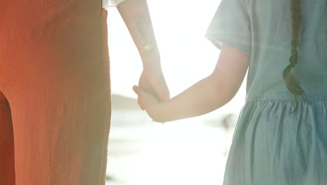 mother and daughter holding hands at sunset