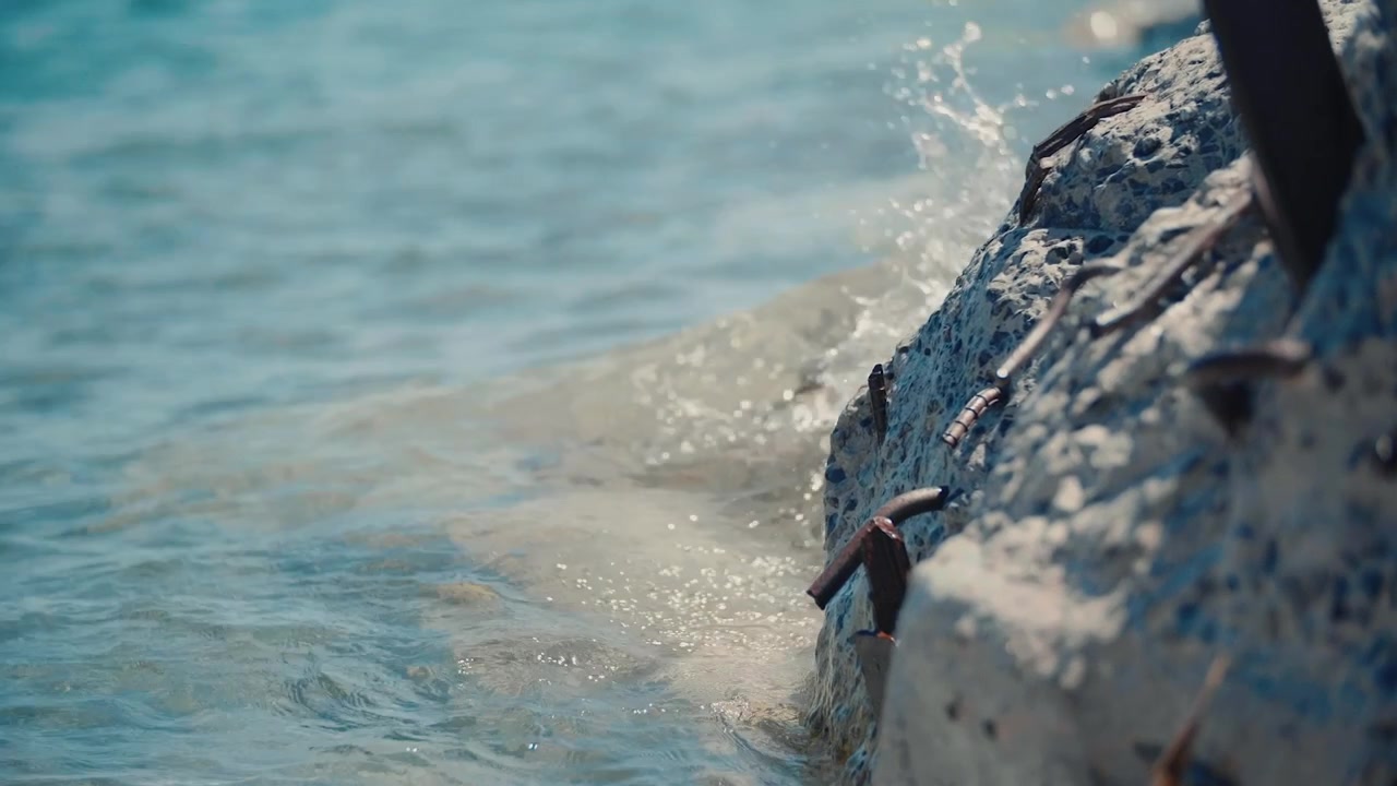 Gentle Waves Lapping Against Concrete Shore with Exposed Rebar