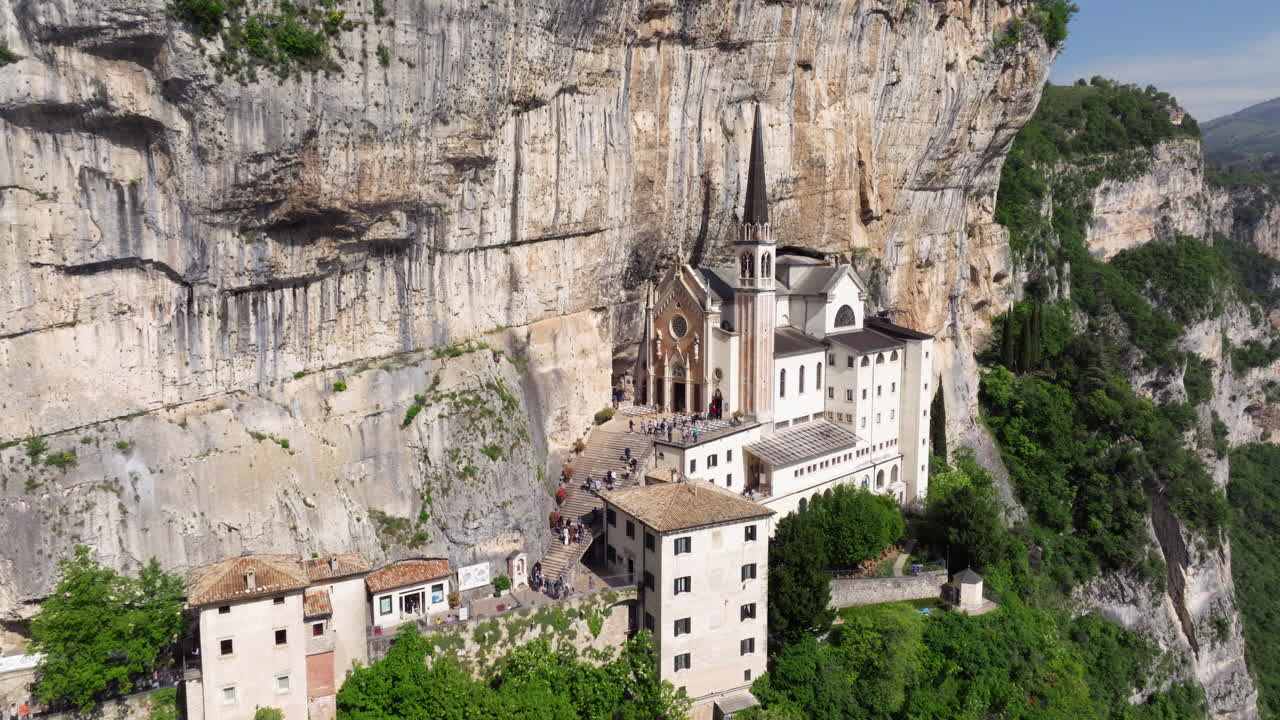 Tourists Visiting The Famous Church Of Madonna della Corona On The Cliff In Italy. - aerial pullback shot