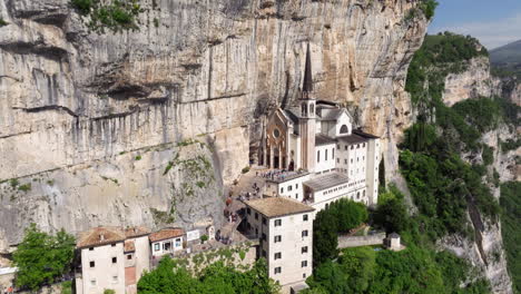 tourists visiting the famous church of madonna della corona on the cliff in italy. - aerial pullback shot