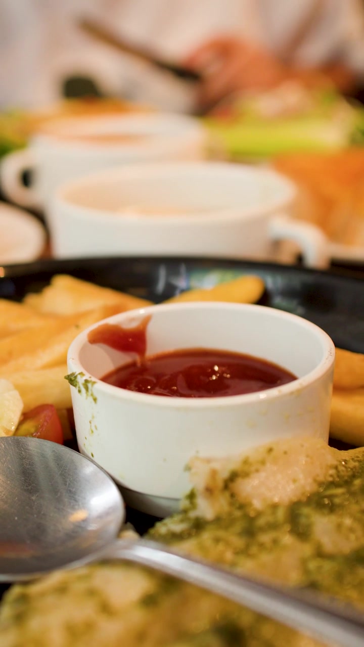 Una lenta panoramica della telecamera su un tavolo di ristorante pieno di patatine fritte, insalata e ciotole di zuppa