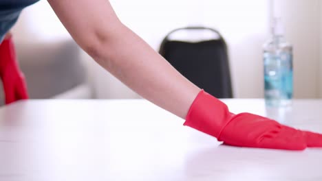 closeup hands wearing red protective household gloves cleaning and disinfects table for protective coivd-19 pandemic