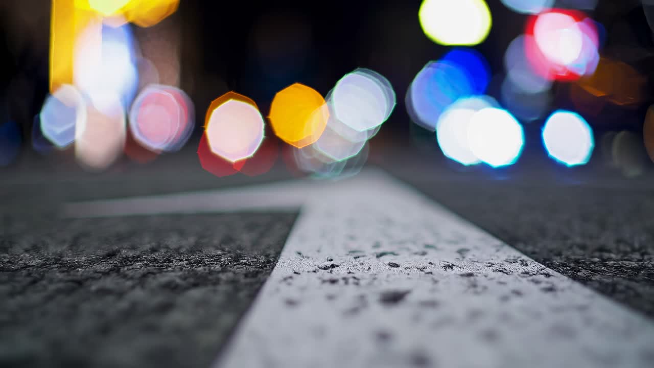 ぼやけた街の明かりが、道路のローアングルでの動画撮影でボケ効果を生み出しています。