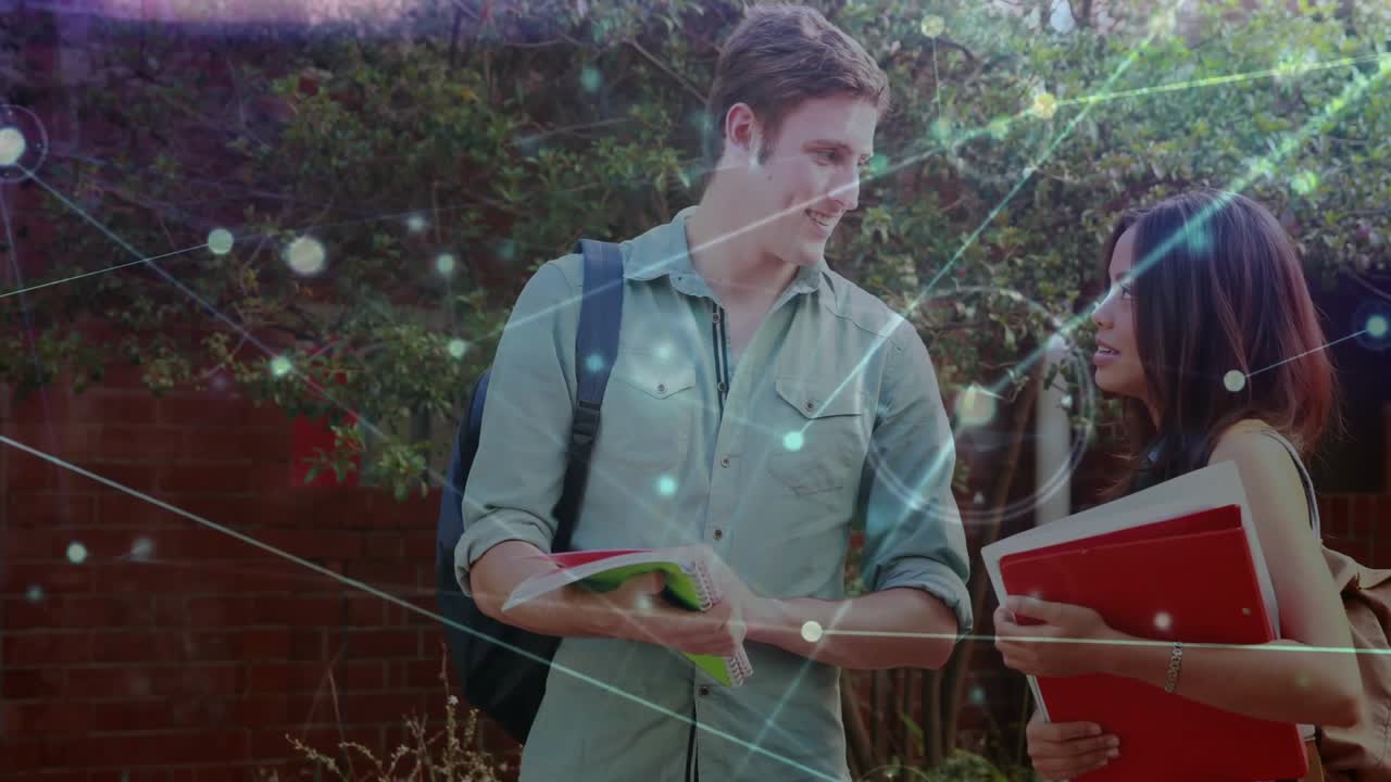 Male student opening green notebook pointing notes to explain to classmate, network overlay pulses