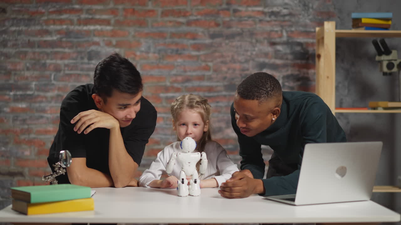 Little girl waves hand to control robot with teachers in lab