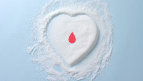 cerca de la gota de sangre sobre el azúcar en forma de corazón sobre fondo azul, cámara lenta.