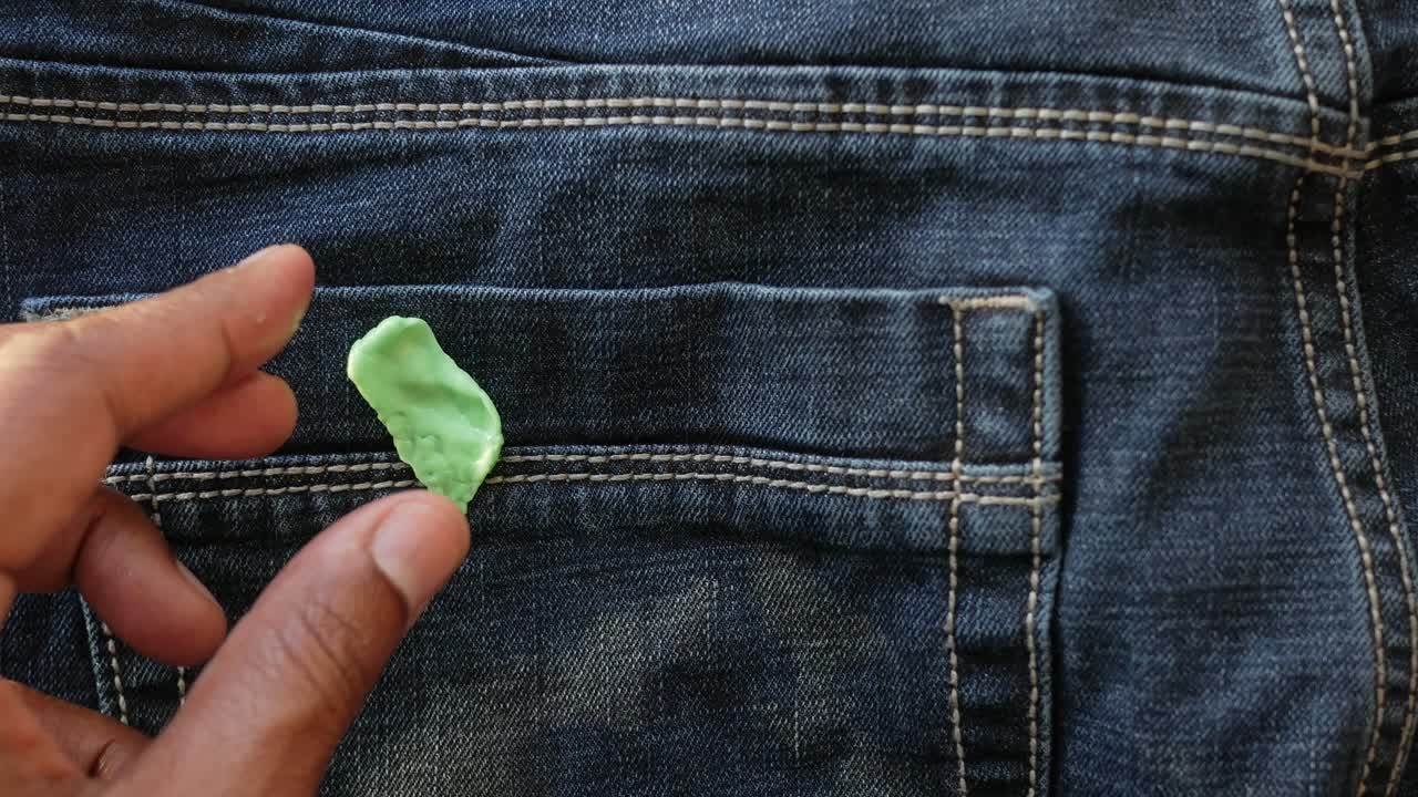 Gum being placed in jeans pocket