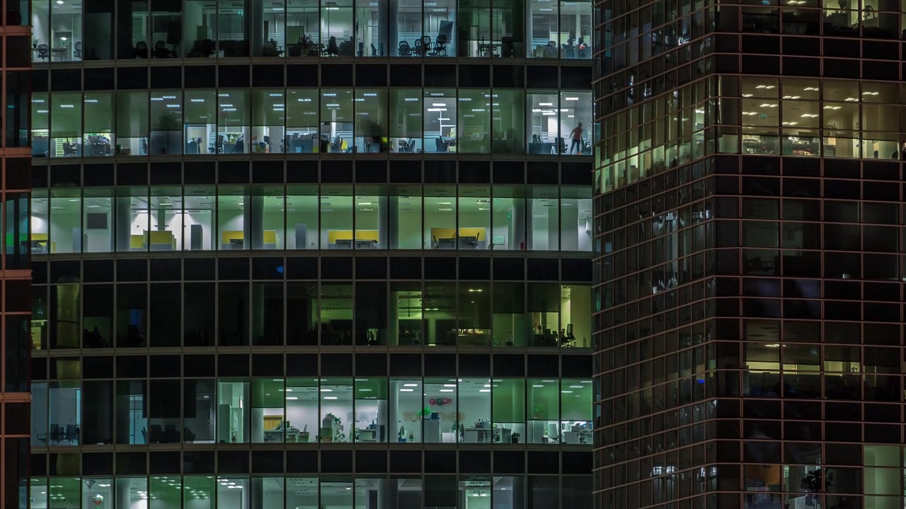 Vista de perto das janelas panorâmicas de escritórios nos arranha-céus do International Business Center da Cidade à noite, timelapse do alto.
