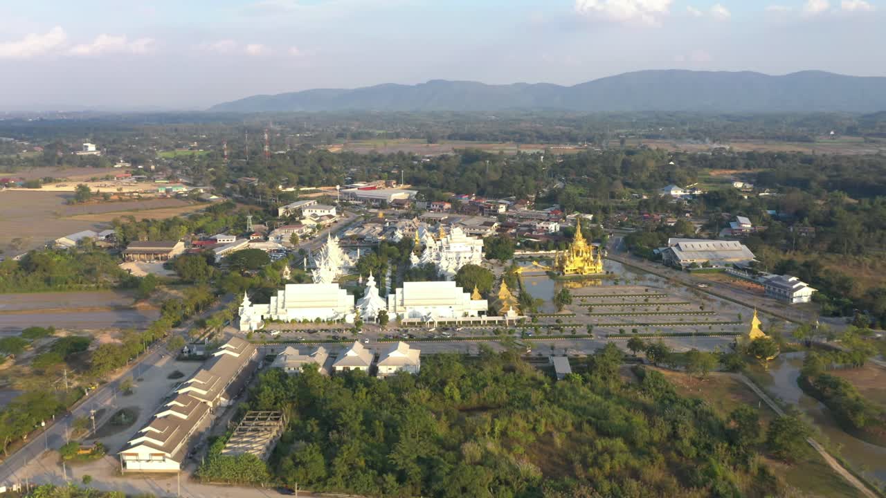 Vue aérienne par drone du Wat Rong Khun, l'immense Temple Blanc bouddhiste et le Temple Doré, avec des montagnes et un paysage à Chiang Rai, Thaïlande