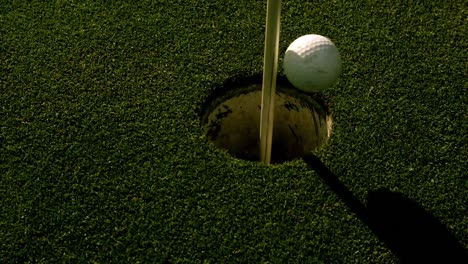 golf ball rolling into the hole on putting green