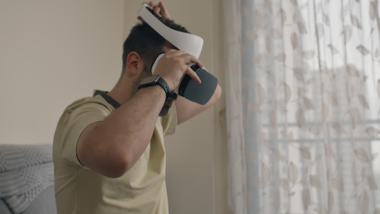 Man puts on VR headset and interacts with virtual interface sitting indoors