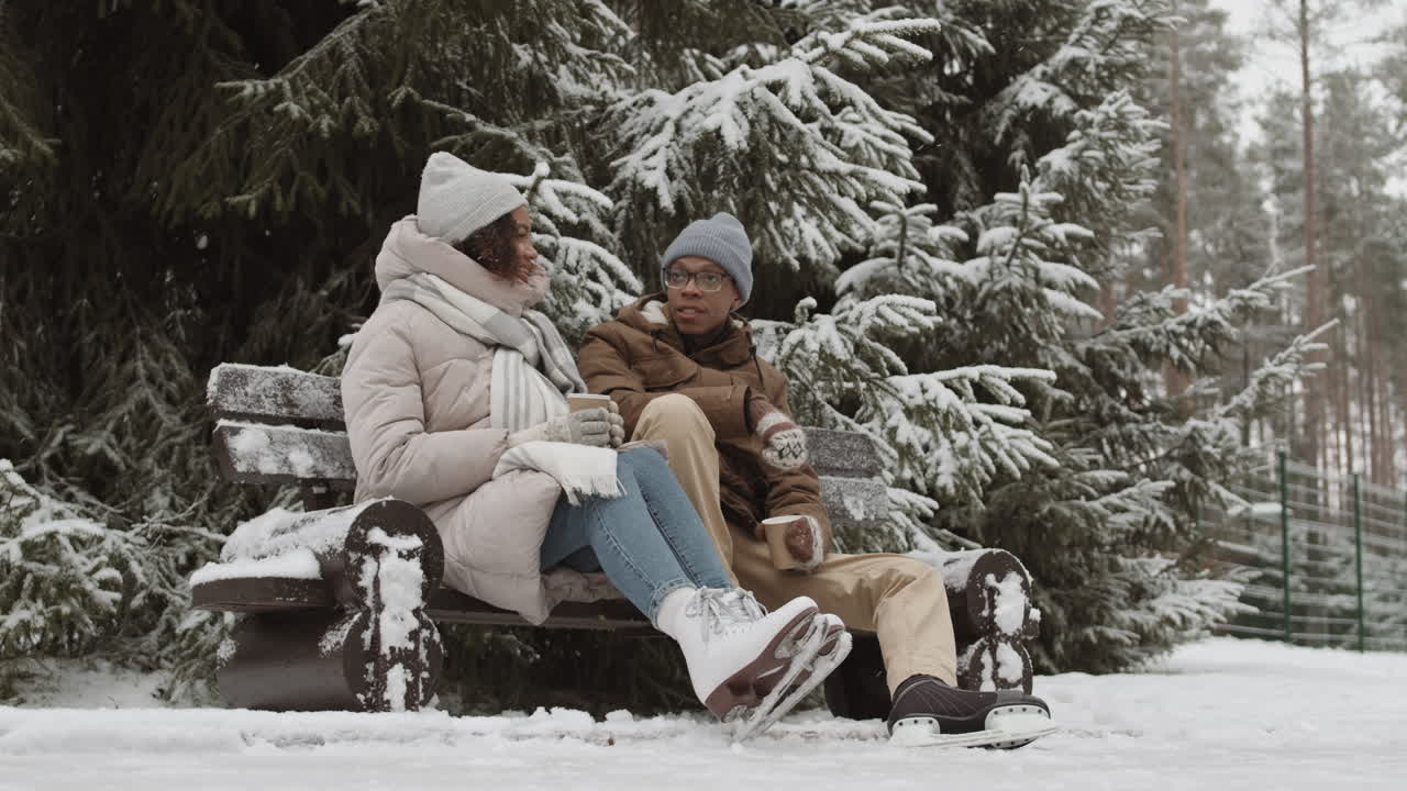 Casal desfrutando de café em parque nevado
