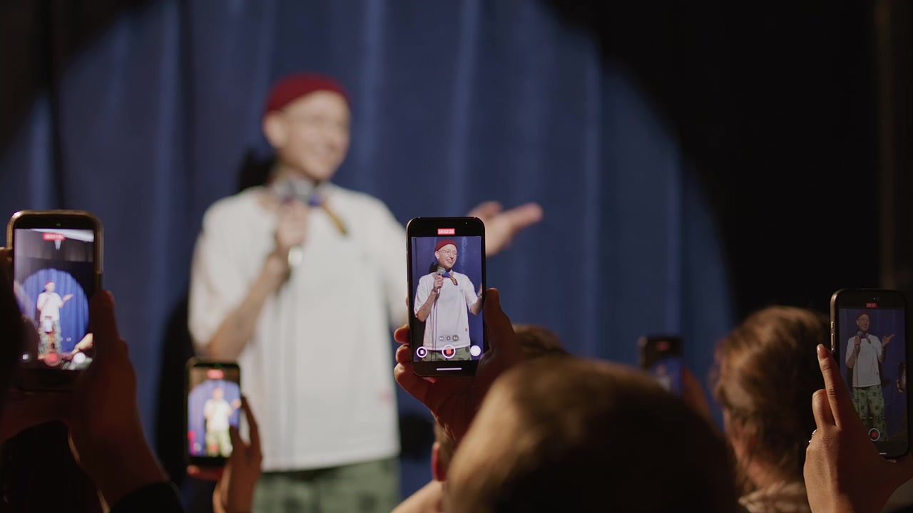 Audience Using Phones to Record Female Comedian Performing Stand Up Show
