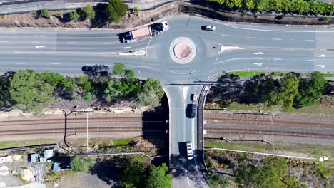 Querformatansicht-Von-Autos-Und-Lastwagen,-Die-Um-Kreisverkehre-Auf-Der-Hauptstraße-Und-Der-Autobahn-Fahren,-Mit-Bahnlinie-Und-Eisenbahnbrücke-Ourimbah-Central-Coast-Australien-Drohnenluftaufnahme