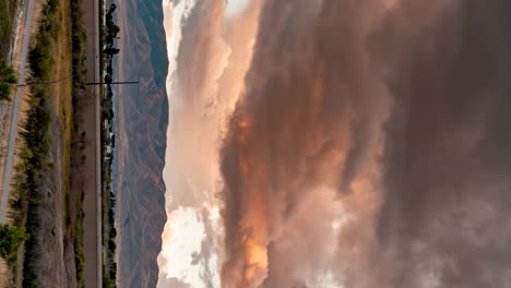 Dark-stormy-clouds-at-sunset-blowing-across-the-sky-above-a-mountain---vertical-orientation-time-lapse