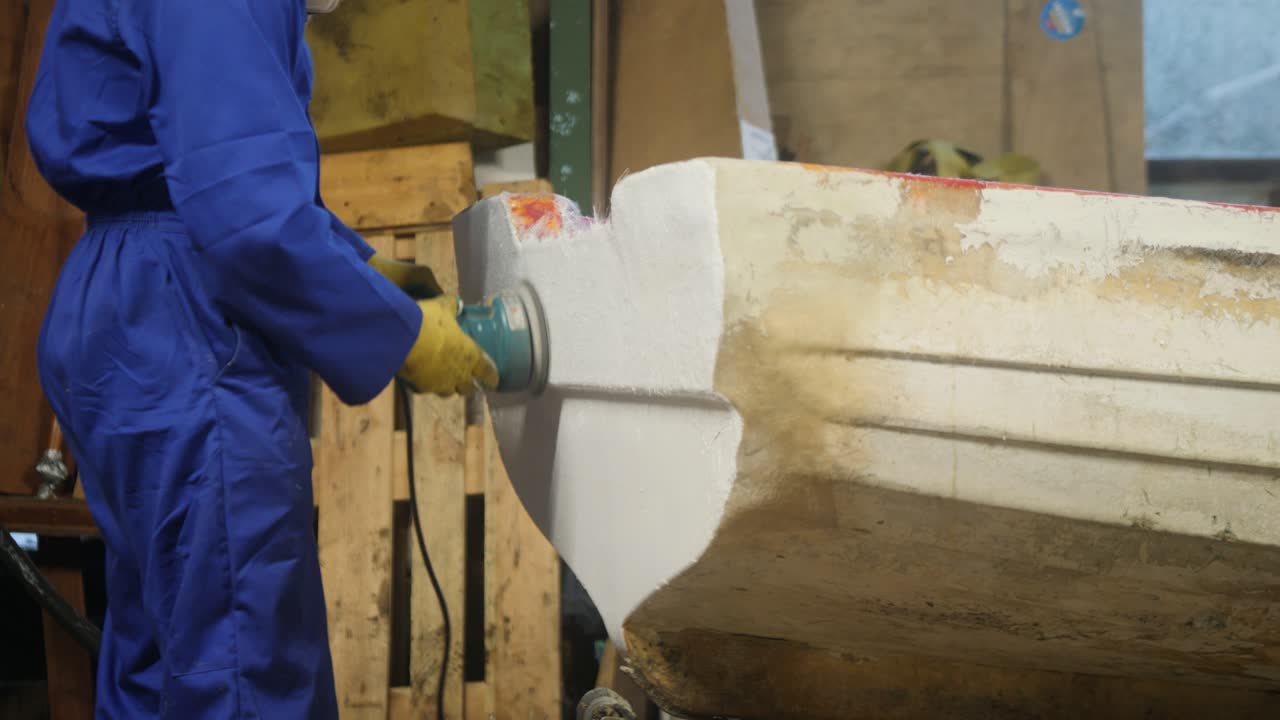 Sanding transom of fiberglass fishing boat with orbital sander