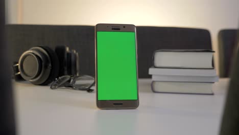 green screen mobile phone standing on the white table