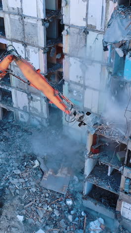 dismantling of a high bulding. excavator demolishing ruins for new construction project. flying above a destruction. vertical video