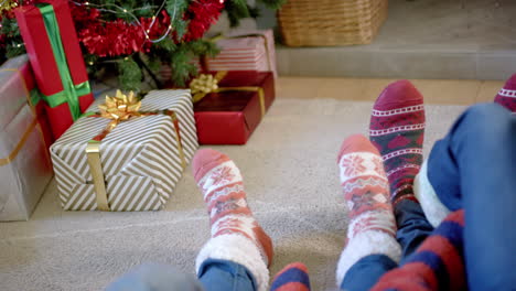 moving feet of family in warm socks by christmas tree and presents, copy space, slow motion