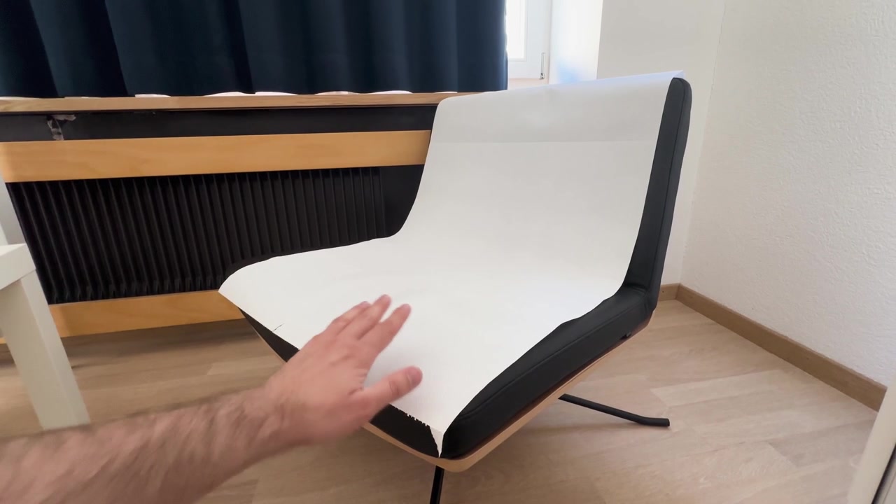 Person placing disposable paper sheet on a chair to maintain hygiene and prevent contamination in a clinical or personal setting.