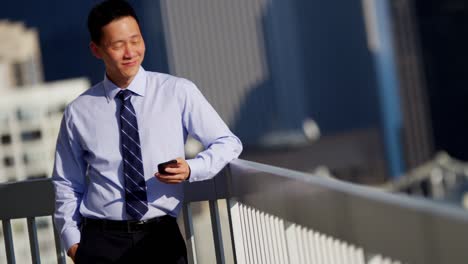 confident ethnic businessman using mobile technology on rooftop