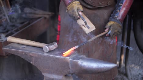 a blacksmith brushing his work on an anvil in his forge, workshop, close up