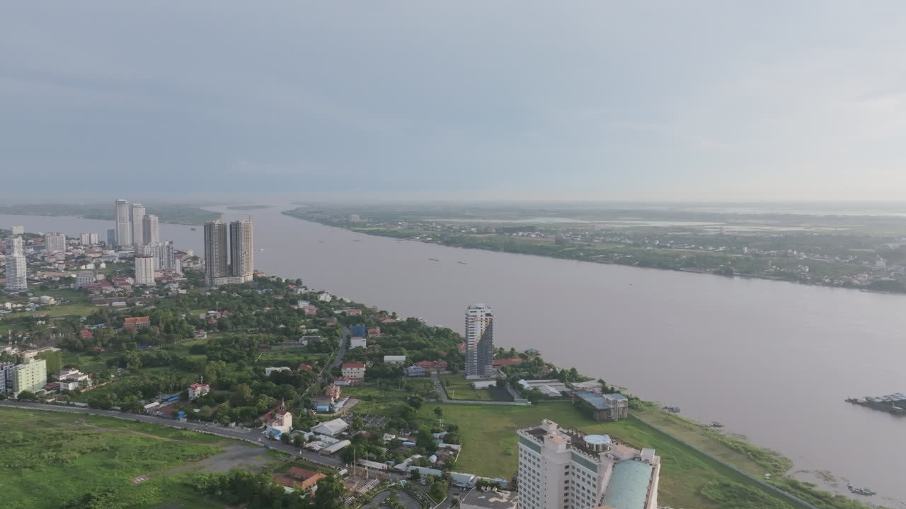 Aerial video of Phnom Penh follows the Mekong River with tall buildings lining the banks