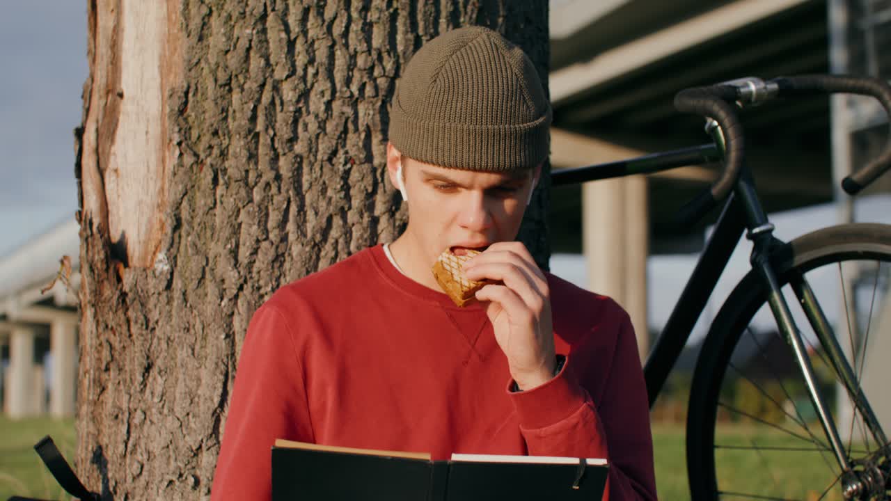 joven leyendo y almorzando al aire libre