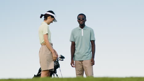 caucasian woman and african american man on the golf course.