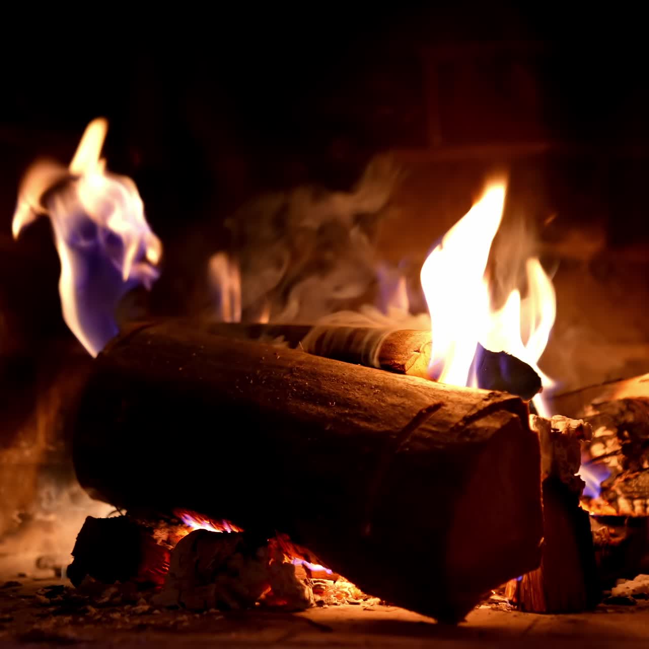 Wooden logs in fire on brick fireplace background. Wood burning in fire flame. Cozy warm fireplace in a country house. Close-up
