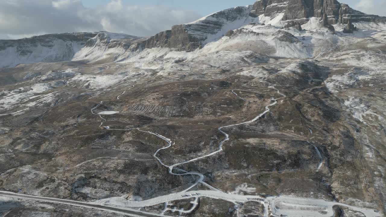 Aerial shot of snowy mountain landscape with winding road, Old Man of Storr, Isle of Skye, Scotland