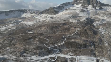 Aerial-shot-of-snowy-mountain-landscape-with-winding-road,-Old-Man-of-Storr,-Isle-of-Skye,-Scotland