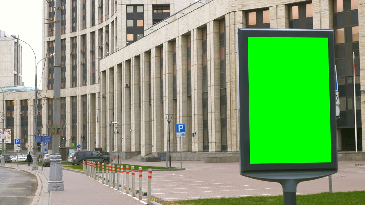 un cartel con una pantalla verde en una calle concurrida.