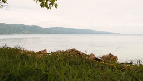 cinematic slow motion shot of the view from a hill moving over grass and pulling up to reveal the ocean and the fantastic view in the philippines, asia, slow motion