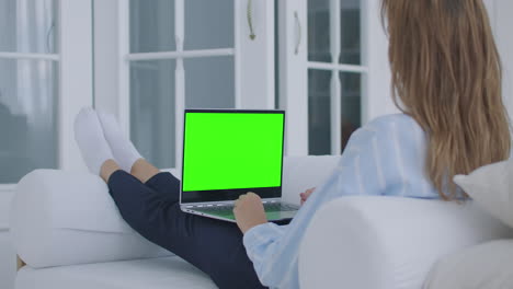 Una-Joven-Sentada-Con-Una-Computadora-Portátil-En-Su-Regazo-Con-Una-Pantalla-Verde-Durante-La-Cuarentena.-Cromakey-En-La-Pantalla-Del-Portátil.-Haz-Una-Videoconferencia-Y-Habla-Con-La-Pantalla-Verde