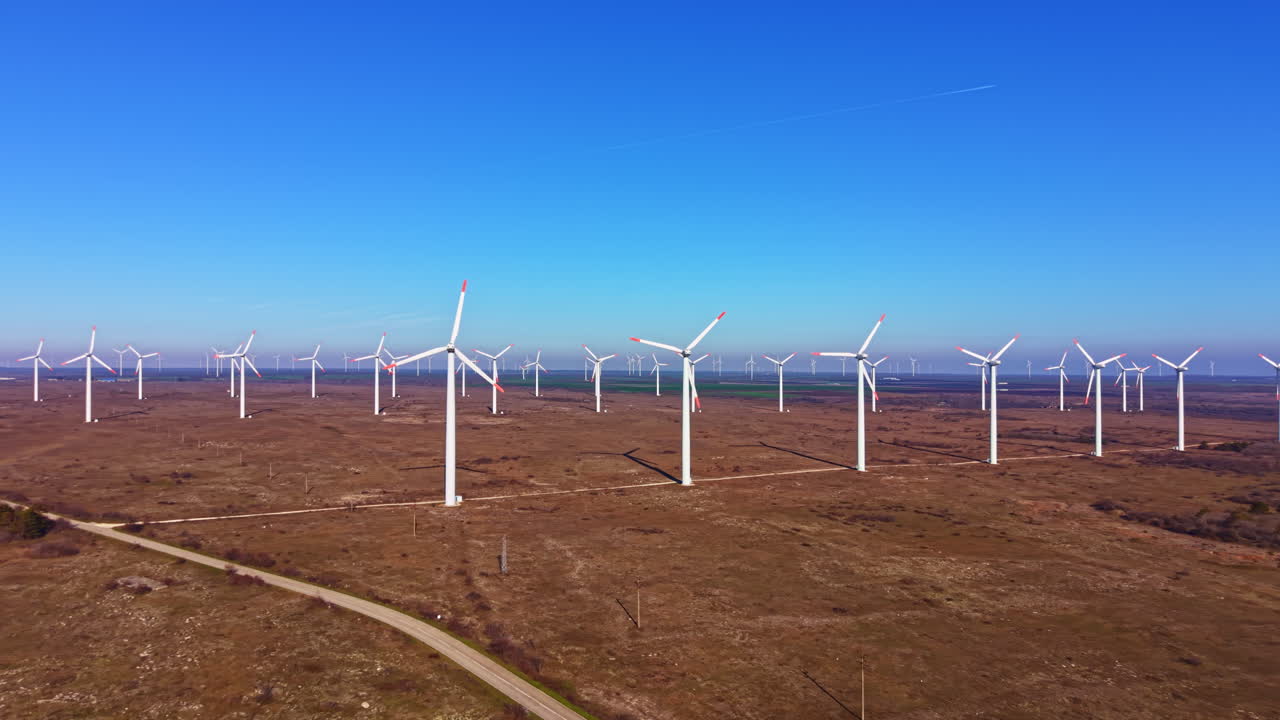 Turbinas eólicas geram energia limpa em um campo aberto, com tempo bom, céu azul e sem nuvens à vista.