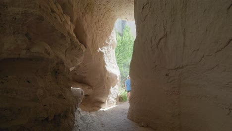 Female-hiker-enters-natural-rock-cave-Red-valley-trail-Cappadoccia