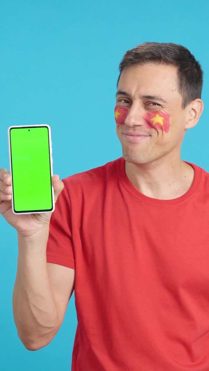 Vietnam supporter looking at his mobile smiling and showing it