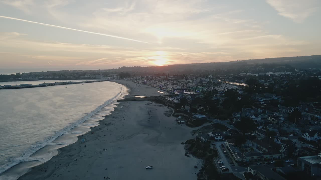 A blue hour drone shot of the Santa Cruz Beach with people walking and enjoying the nightlife of a beach atmosphere on the Pacific Ocean Beach