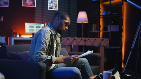 vertical video young adult sitting on couch and reading research papers with analytics
