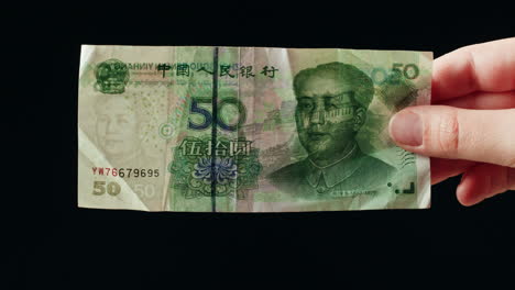 hand holding a 50 chinese yuan banknote