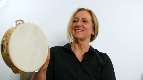 Close-up-view-of-a-woman-playing-tambourine,-smiling,-still-shot