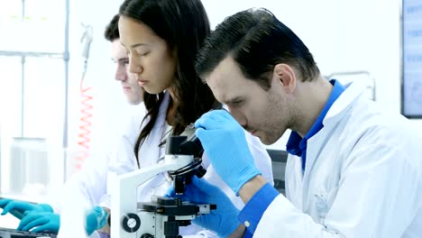 científicos o químicos que utilizan microscopios y otras tecnologías. científicos en equipo trabajando juntos en un laboratorio. resolución de 4k.