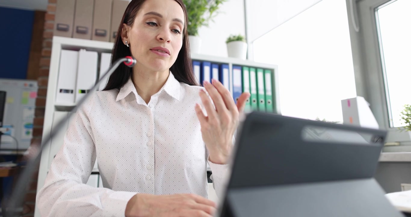 Una donna professionista in un ufficio utilizza un tablet per partecipare a una riunione virtuale.