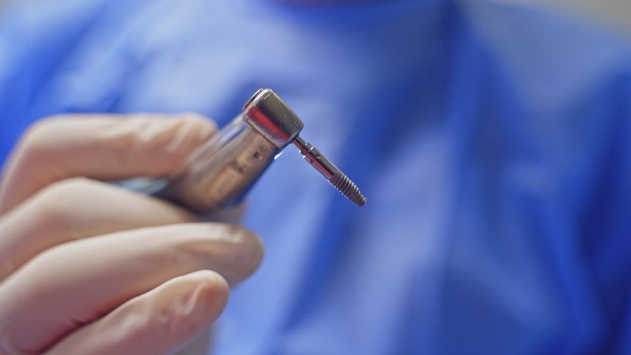 Primo piano di un trapano dentale. Mani del chirurgo dentista con guanti protettivi e lo strumento durante l'operazione.