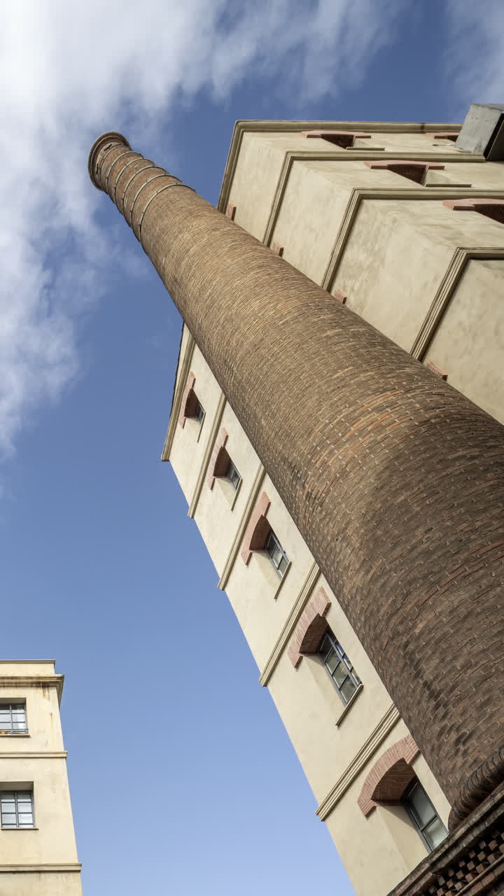 Old factory chimney and apartment buildings in barcelona in vertical