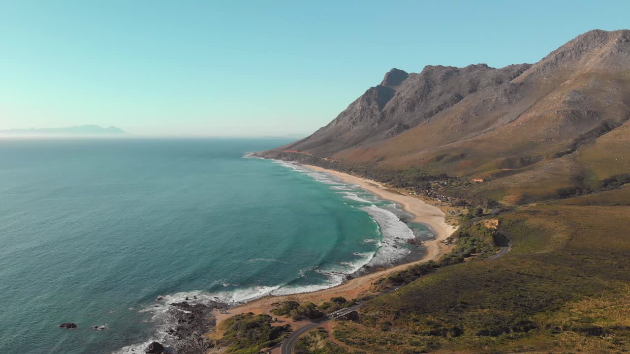 Aerial drone view of camera pan up from coastal road to mountain pass and ocean view