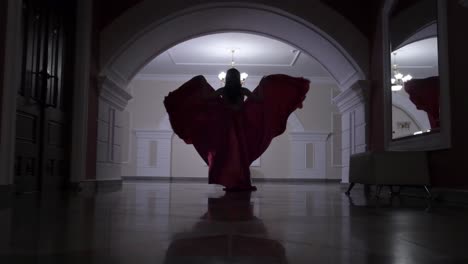 woman in a red gown walking through a grand hallway