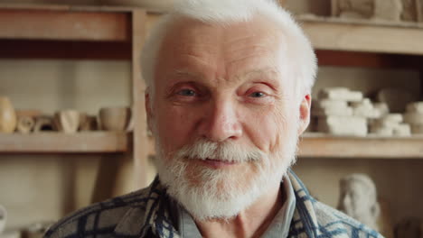 portrait of cheerful elderly potter in workshop