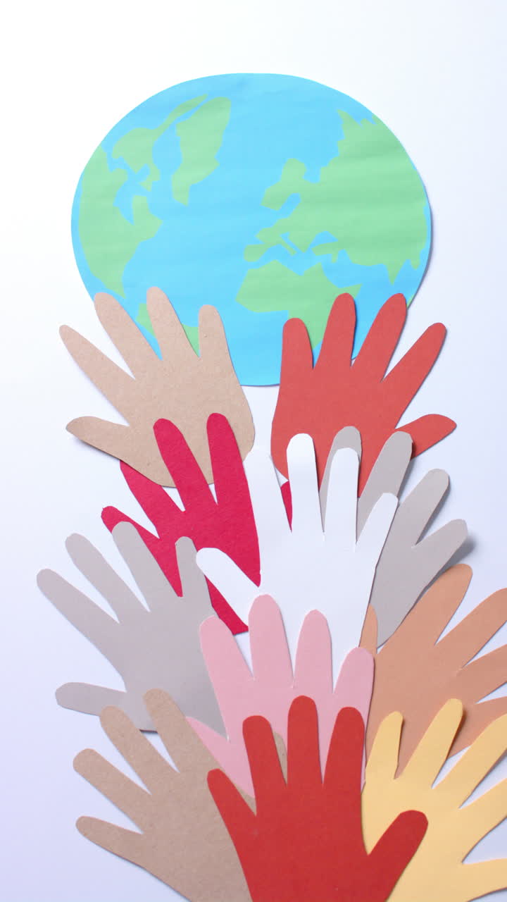 Vertical video of hands with globe made of colourful paper on white background with copy space